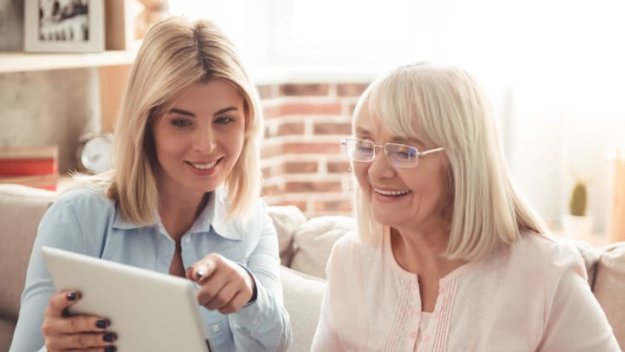 Senior Living Resident Reviewing Photos With Daughter