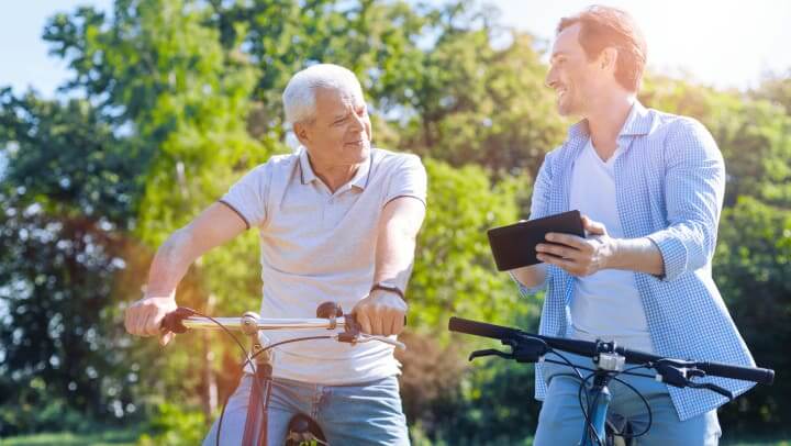 Senior Living Resident Biking With Young Man