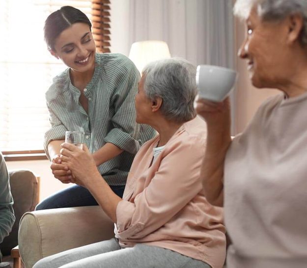 Caregiver helps senior living residents drink from cup