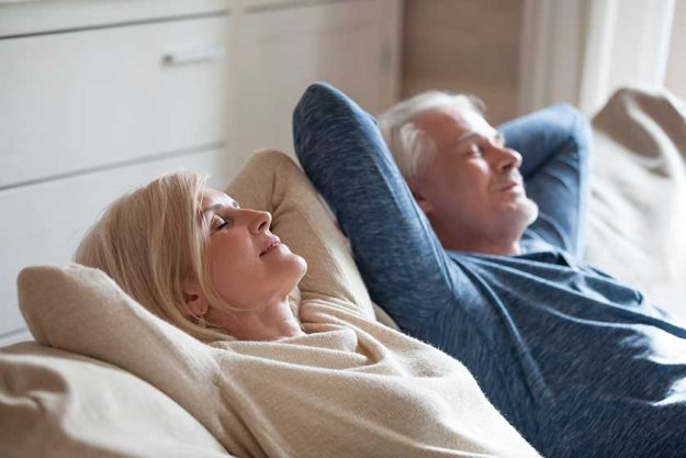Calm senior mature couple relaxing on soft comfortable sofa having daytime nap together Calm senior mature couple relaxing on soft comfortable sofa having daytime nap together