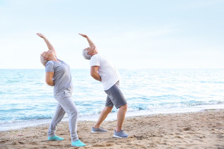 Mature couple practicing yoga at sea resort