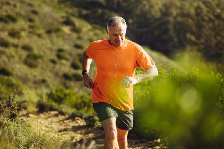 Senior athletic person trail running on a hill