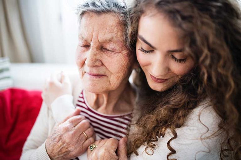 A teenage girl with grandmother at home, hugging