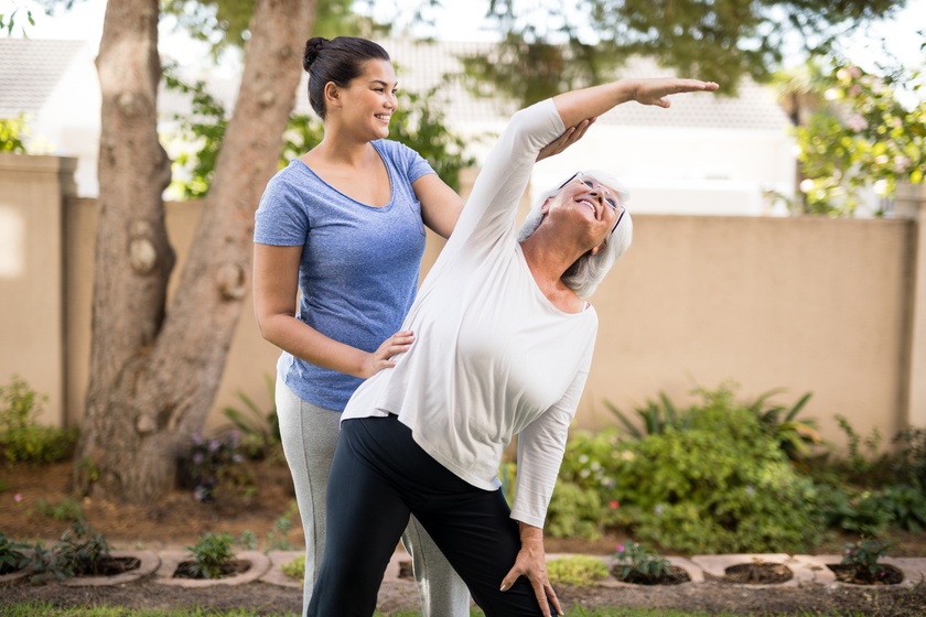Smiling trainer instructing senior woman while exercising A Guide To Age-Friendly Recreational Sports