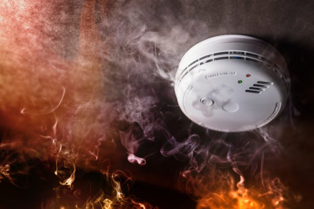Smoke detector and fire alarm in action background Fire Safety Tips For Seniors