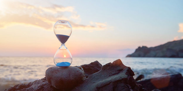 Hourglass with blue falling sand inside.