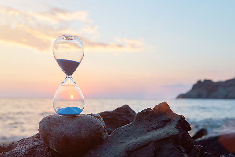 Hourglass with blue falling sand inside.