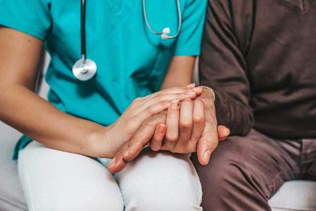 Nurse holding hand of senior man in rest home