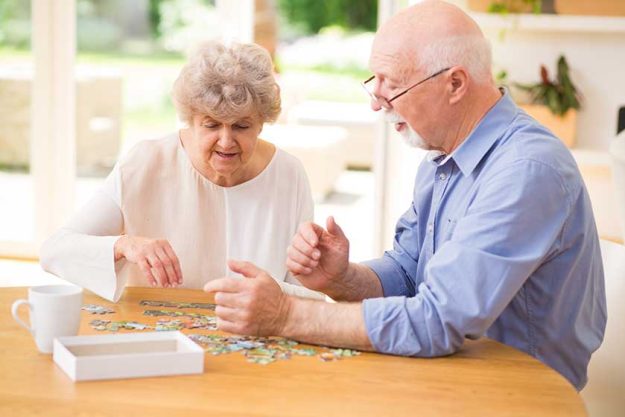 Elder couple assembling the puzzle together Elder couple assembling the puzzle together