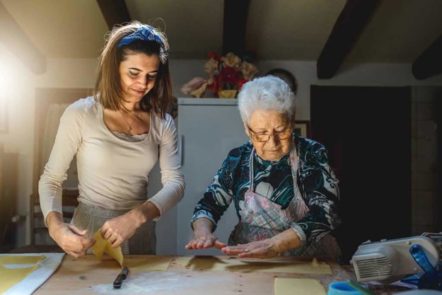 Grandmother and granddaughter preparing dough for fresh homemade pasta.