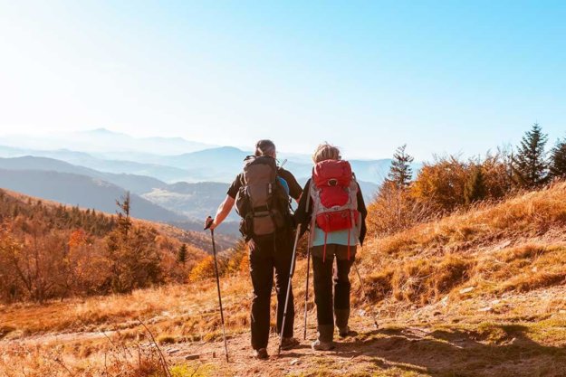 Two old people retired hike through the autumn mountains after quarantine