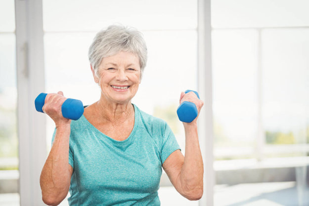 Portrait of smiling senior woman holding dumbbell Portrait of smiling senior woman holding dumbbell