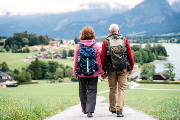 A rear view of senior pensioner couple hiking in nature, holding hands. How To Combat Boredom In Your Retirement Years