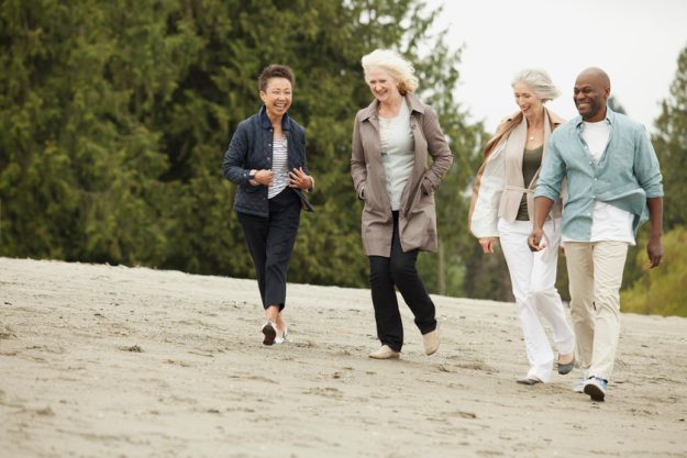 mature friends walking along the beach
