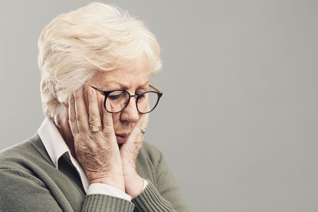 Sad lonely elderly woman posing with head in hands Sad lonely elderly woman posing with head in hands