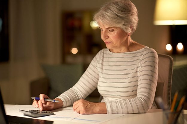 senior woman with laptop counting on calculator