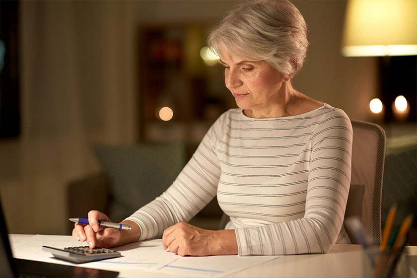 senior woman with laptop counting on calculator senior woman with laptop counting on calculator