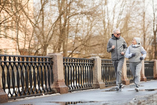 Full length wide angle view at active senior couple running outdoors in winter Full length wide angle view at active senior couple running outdoors in winter