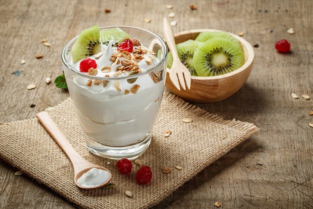 Homemade yogurt or sour cream in a glass with kiwi – on the wood Homemade yogurt or sour cream in a glass with kiwi - on the wood