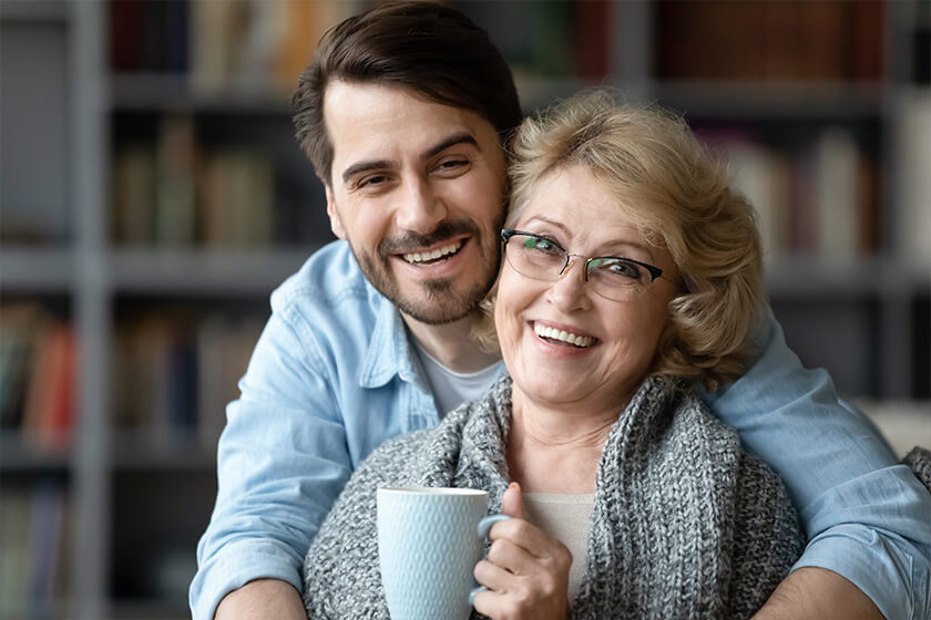 In living room pretty elderly mother in sweater holding cup In living room pretty elderly mother in sweater holding cup