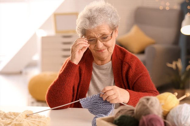Senior woman knitting warm sock at table Senior woman knitting warm sock at table