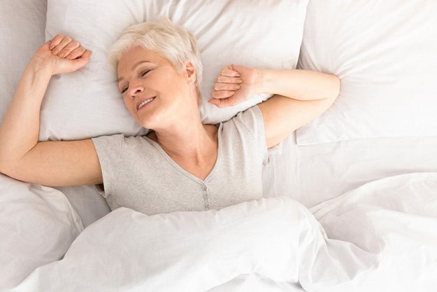 Senior woman lying down in her bed at home Senior woman lying down in her bed at home