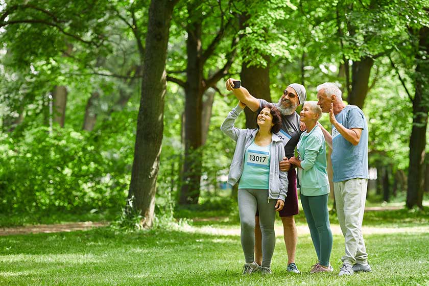 Group of joyful sporty senior adult men and women standing together in park Group of joyful sporty senior adult men and women standing together in park