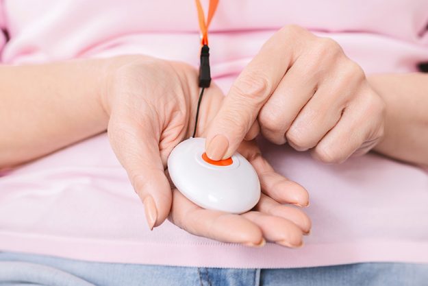 Alarm button for emergency call in senior woman hands