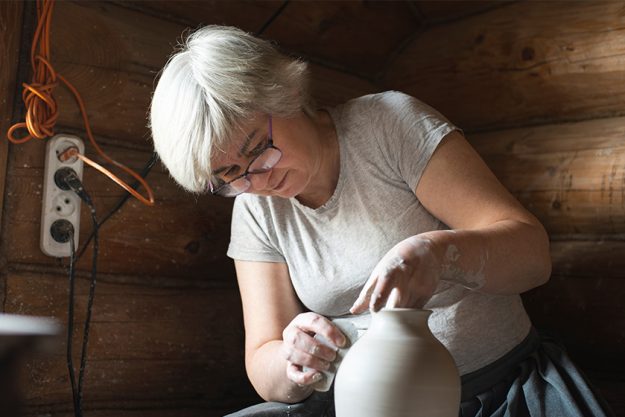 Female potter making a clay pot on a pottery wheel in her workshop Female potter making a clay pot on a pottery wheel in her workshop