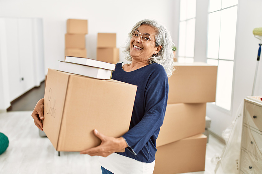 Middle age grey-haired woman smiling happy holding books cardboard box Middle age grey-haired woman smiling happy holding books cardboard box