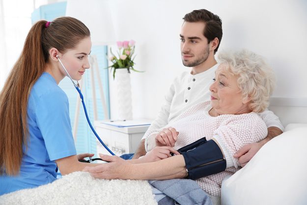Nurse measuring woman’s blood pressure with tonometer indoors Nurse measuring woman's blood pressure with tonometer indoors