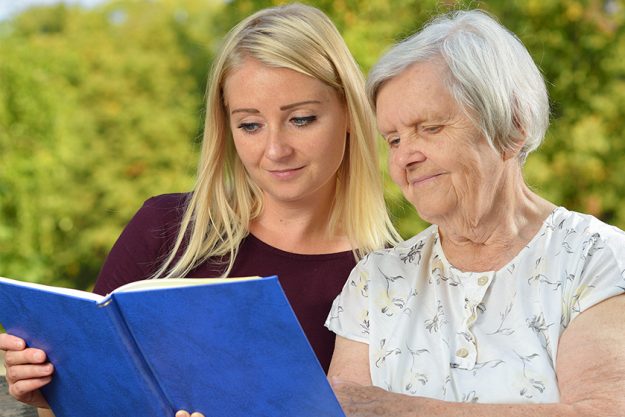 Young woman reading a book elderly woman in the park