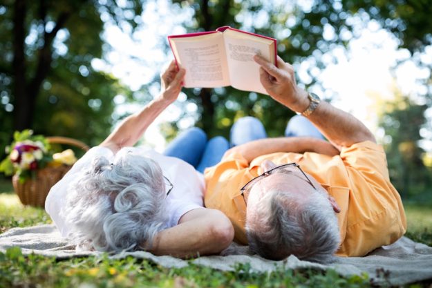 Senior couple resting at park, reading a book Senior couple resting at park, reading a book