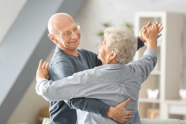 Cute elderly couple dancing at home
