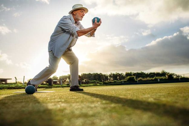 Side view of an elderly man playing boules