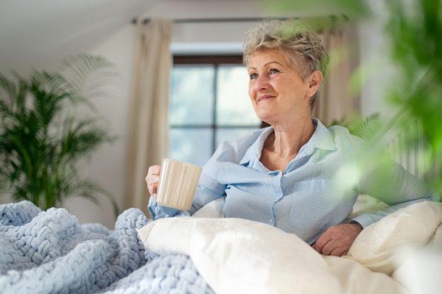 Happy senior woman with a hot drink in bed at home, relaxing. Happy senior woman with a hot drink in bed at home, relaxing.