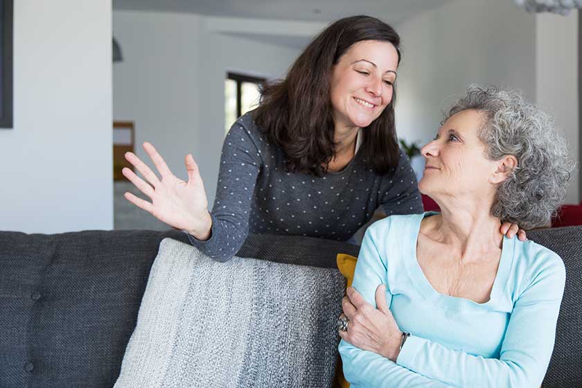 Cheerful young woman talking to senior mother in living room Cheerful young woman talking to senior mother in living room