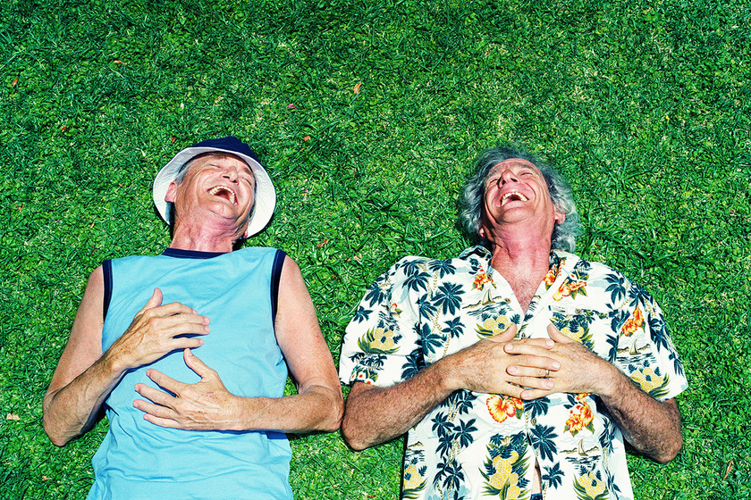 Two mature men lying on grass, laughing, overhead view