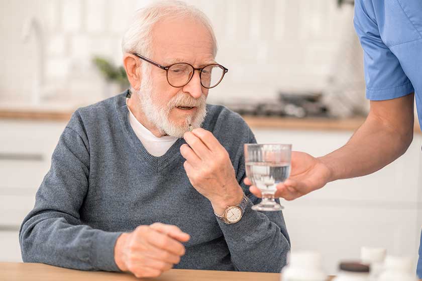 Pensioner taking a medicine under the supervision of his nurse Pensioner taking a medicine under the supervision of his nurse