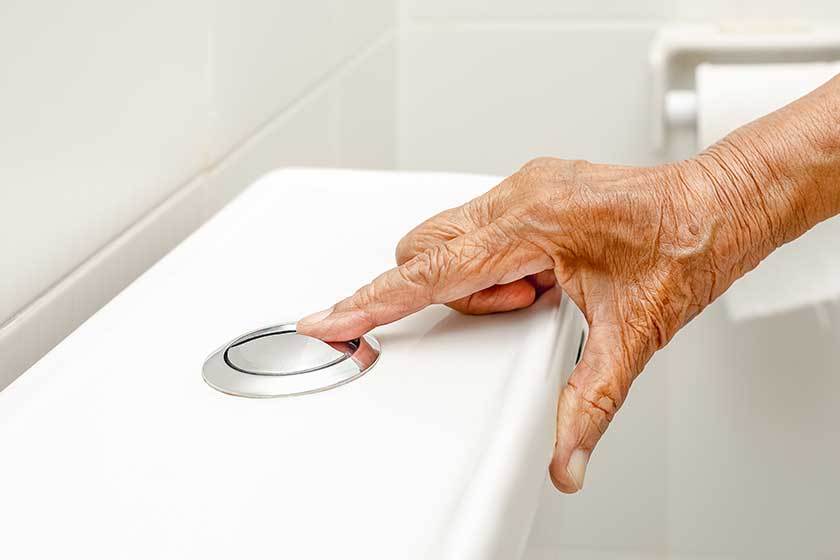Elderly woman hand flushing toilet