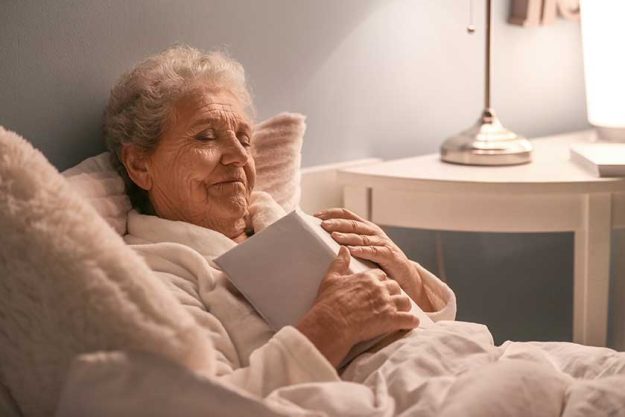 Senior woman with book sleeping in bed at night Senior woman with book sleeping in bed at night