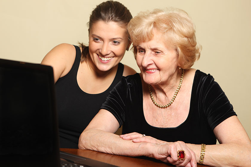 Granddaughter showing her grandmother something on laptop