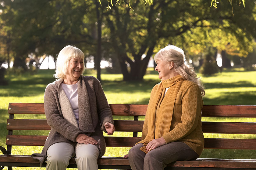 Happy old women sitting on bench in park Happy old women sitting on bench in park