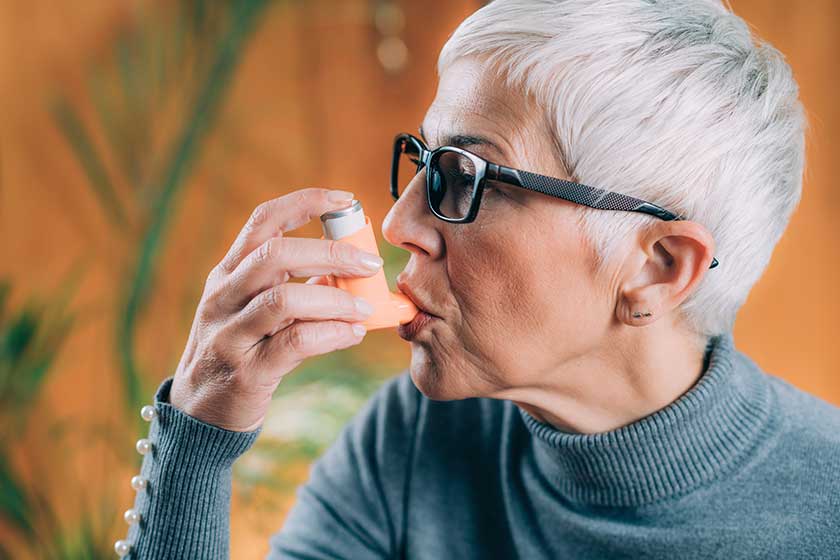 Senior Woman Using Asthma Inhaler with Extension Tube Senior Woman Using Asthma Inhaler with Extension Tube