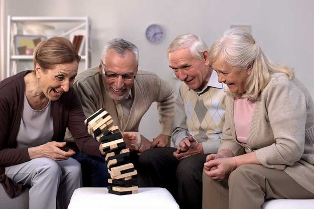 Happy mature people playing board game together nursing home Happy mature people playing board game together nursing home