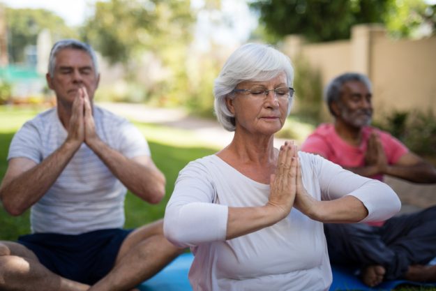 Senior people with closed eyes meditating in prayer position How The Environment In Retirement Communities In Philadelphia, PA Keeps Your Respiratory System Healthy