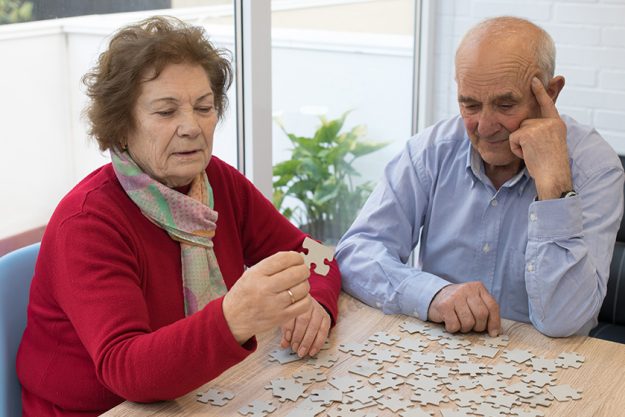 older couple making puzzle on the table