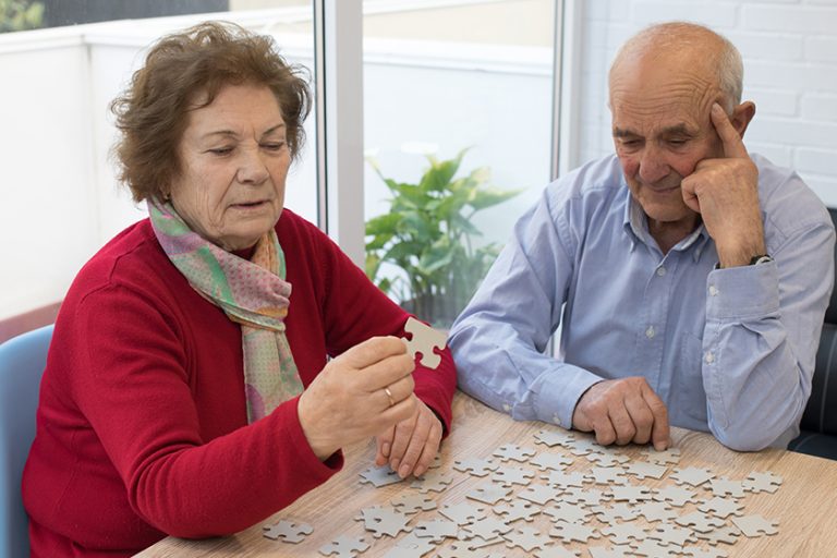 older couple making puzzle on the table