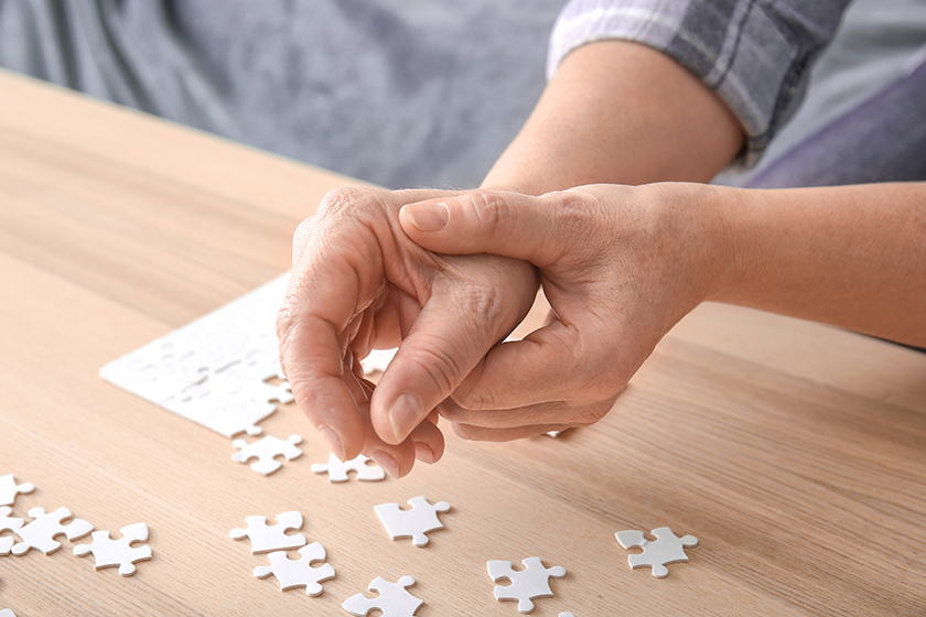 Senior woman suffering from Parkinson syndrome doing puzzle at home Senior woman suffering from Parkinson syndrome doing puzzle at home
