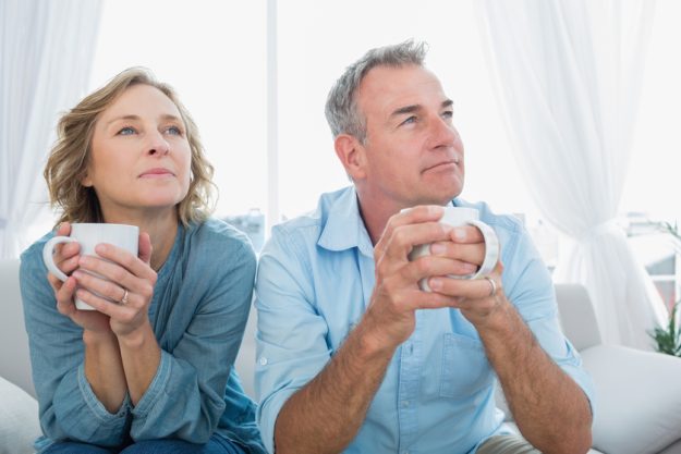 Thoughtful middle aged couple sitting on the couch having coffee looking away at home in the living room X Reasons Why A Resort-Style Senior Living In Leesport, PA Is Your Best Option